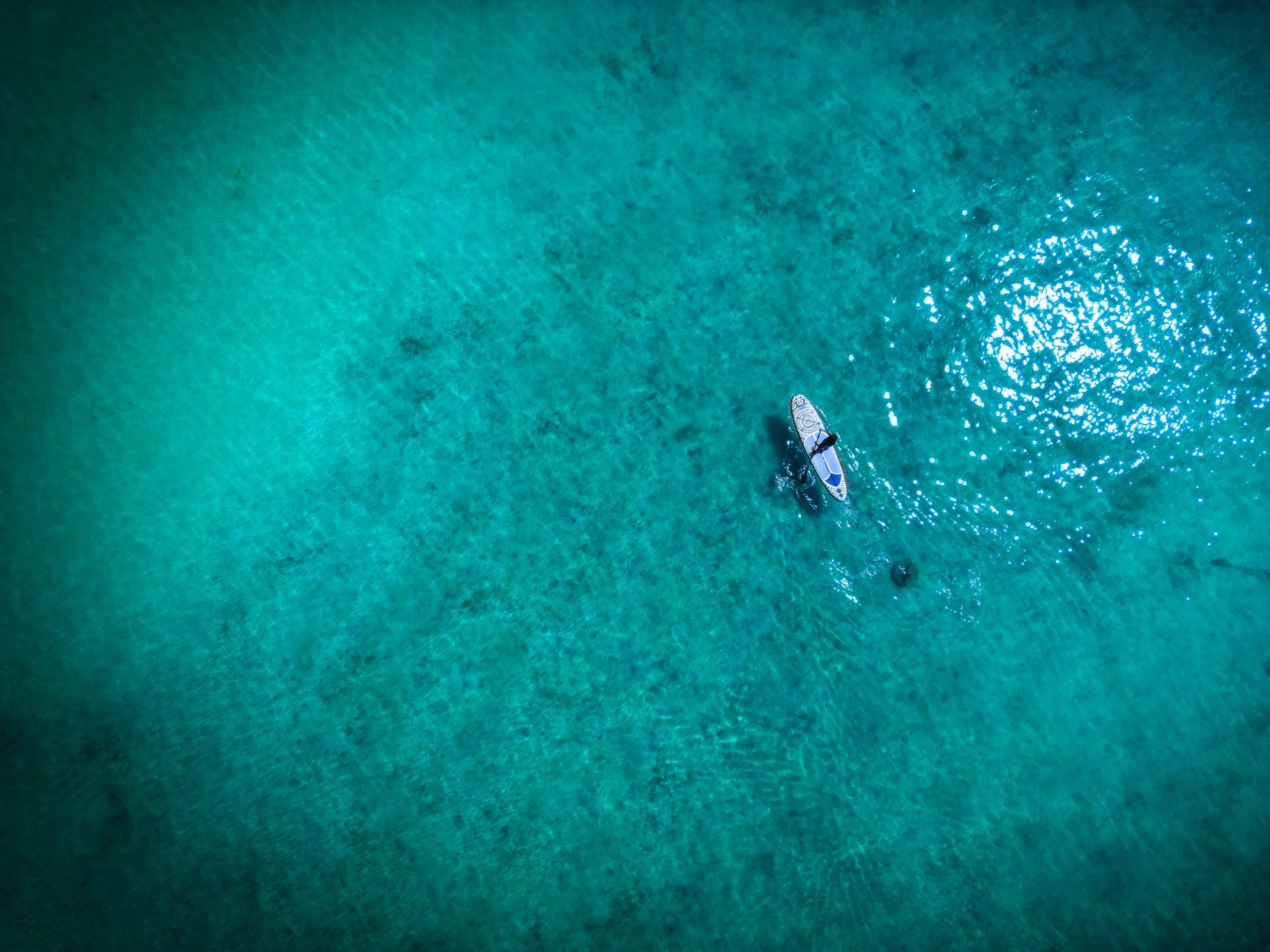 A boat anchored over clear shallows during the mid-year season