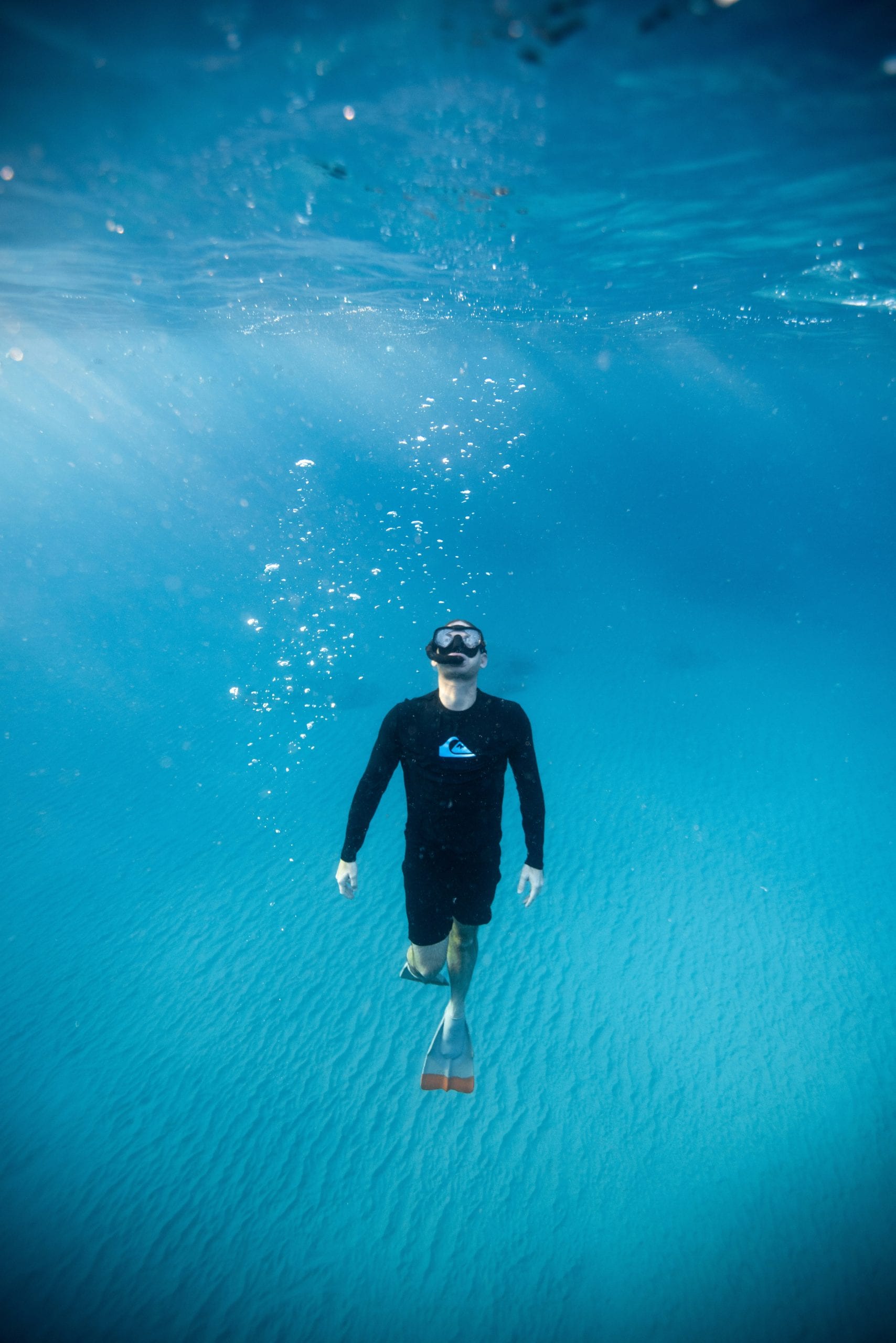 A freediver descending on a single breath in clear blue water