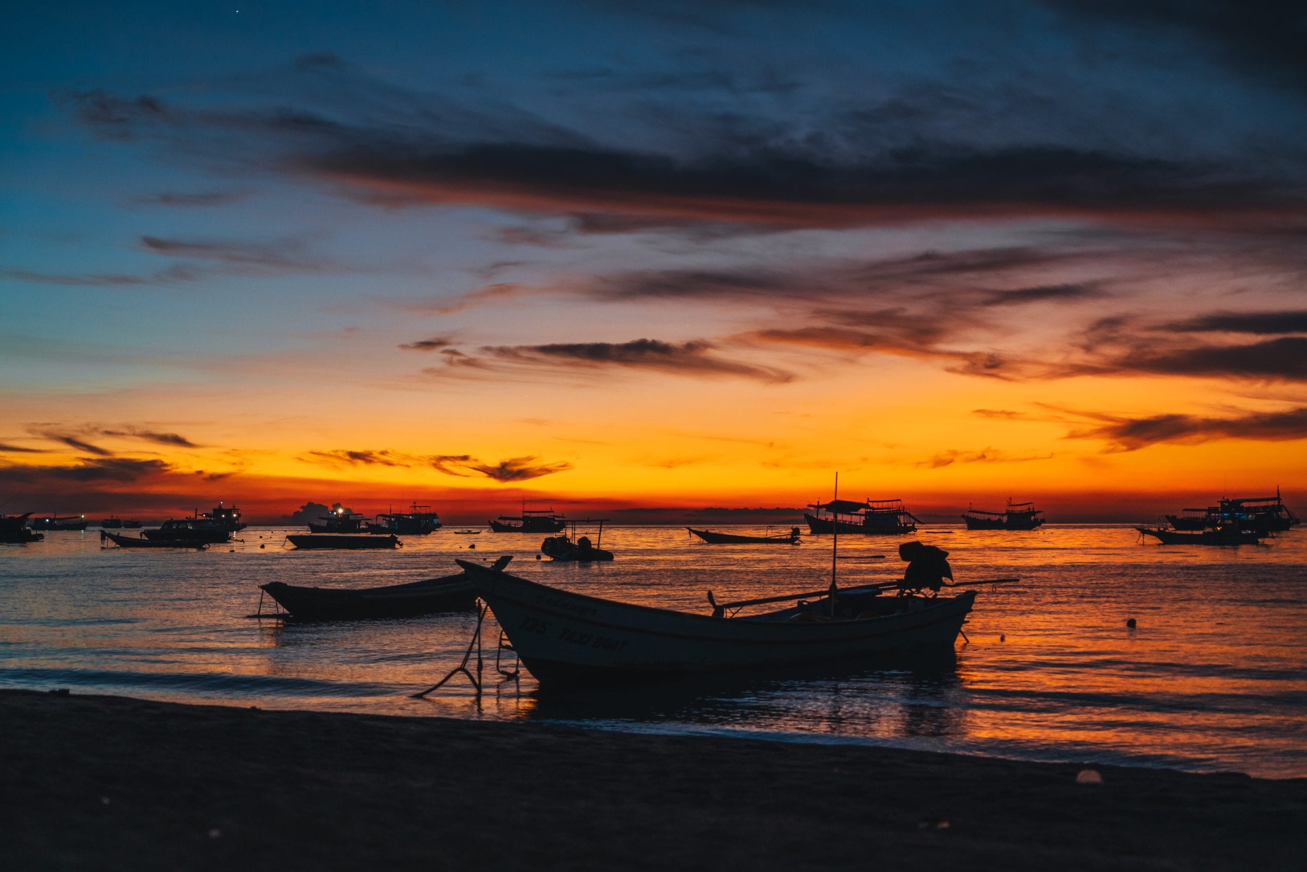 Freedom Beach at sunset, boats silhouetted offshore