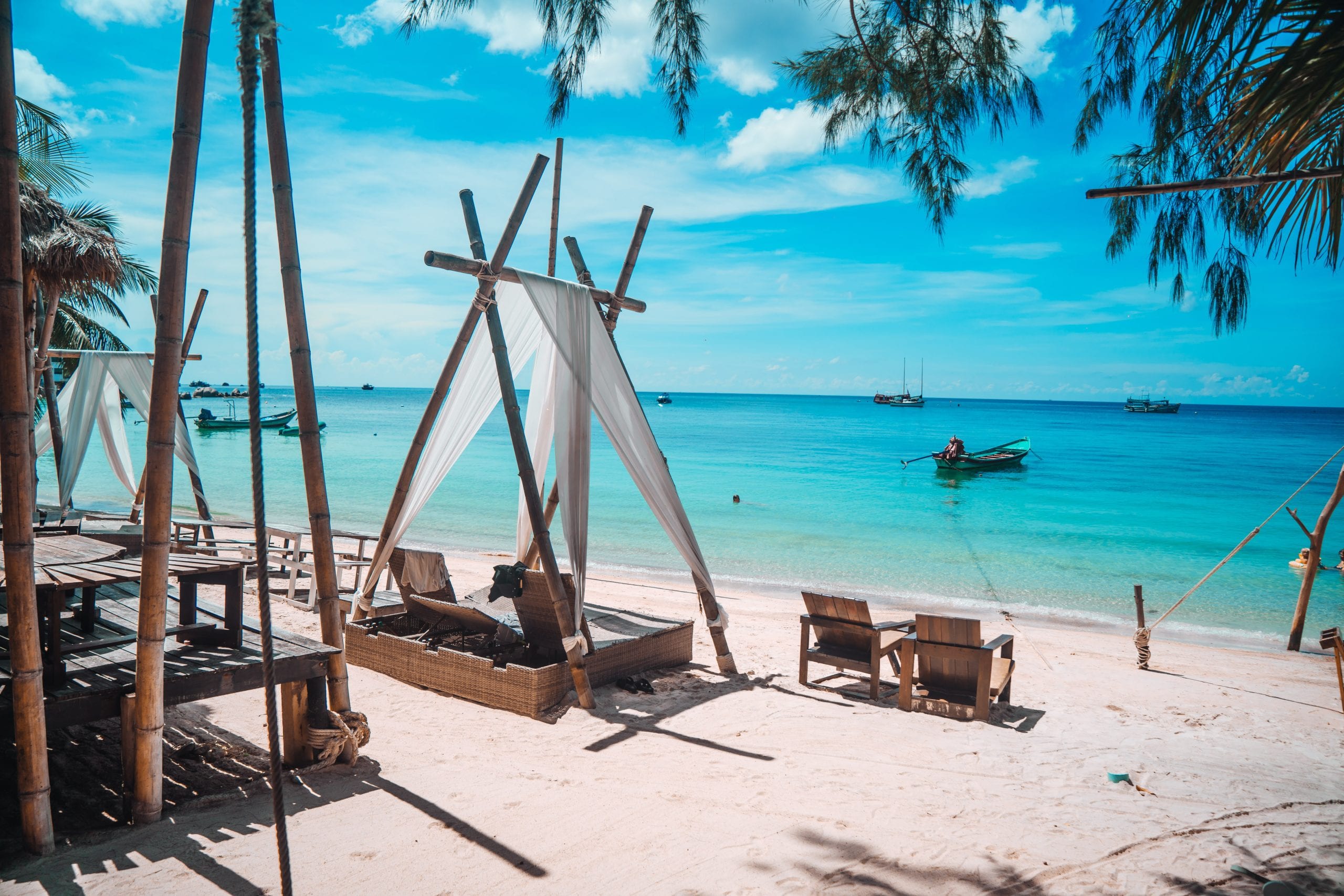 Daybeds and low tables set out on the sand at a Koh Tao beach bar