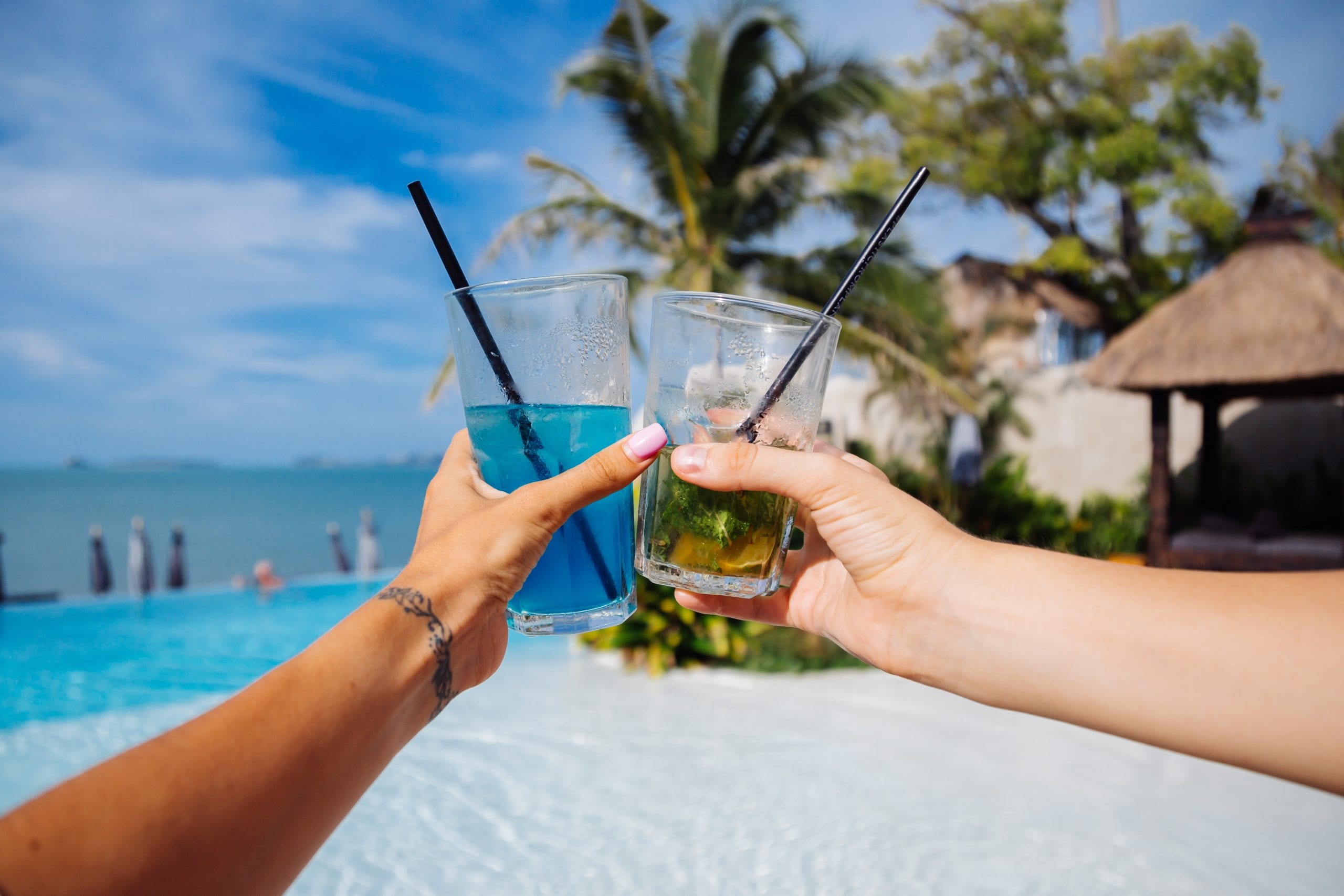 Two cocktails touched together over the sand at sunset